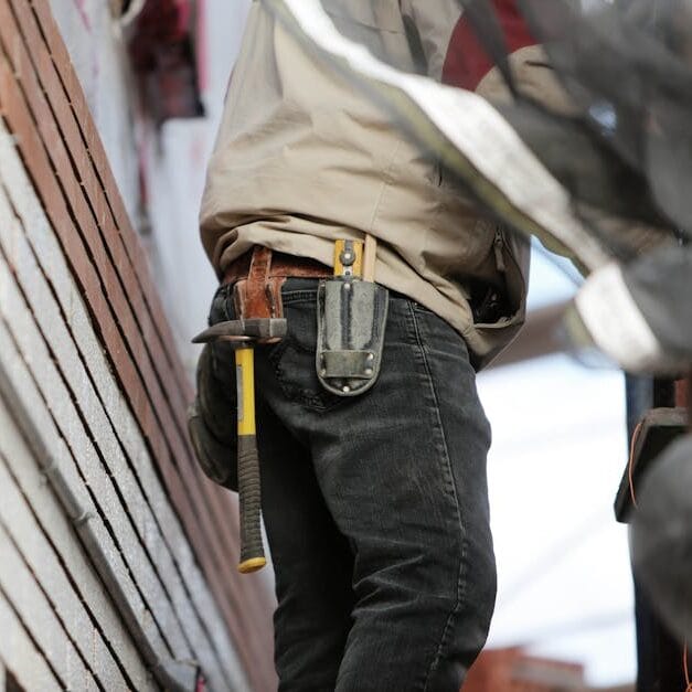 Close-up of a construction worker with hammer and tools, focused on the job.